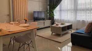 A modern living room with a dining area, a flat-screen TV, and a large window with curtains. - Arte Plus by Poly City (Kuala Lumpur)