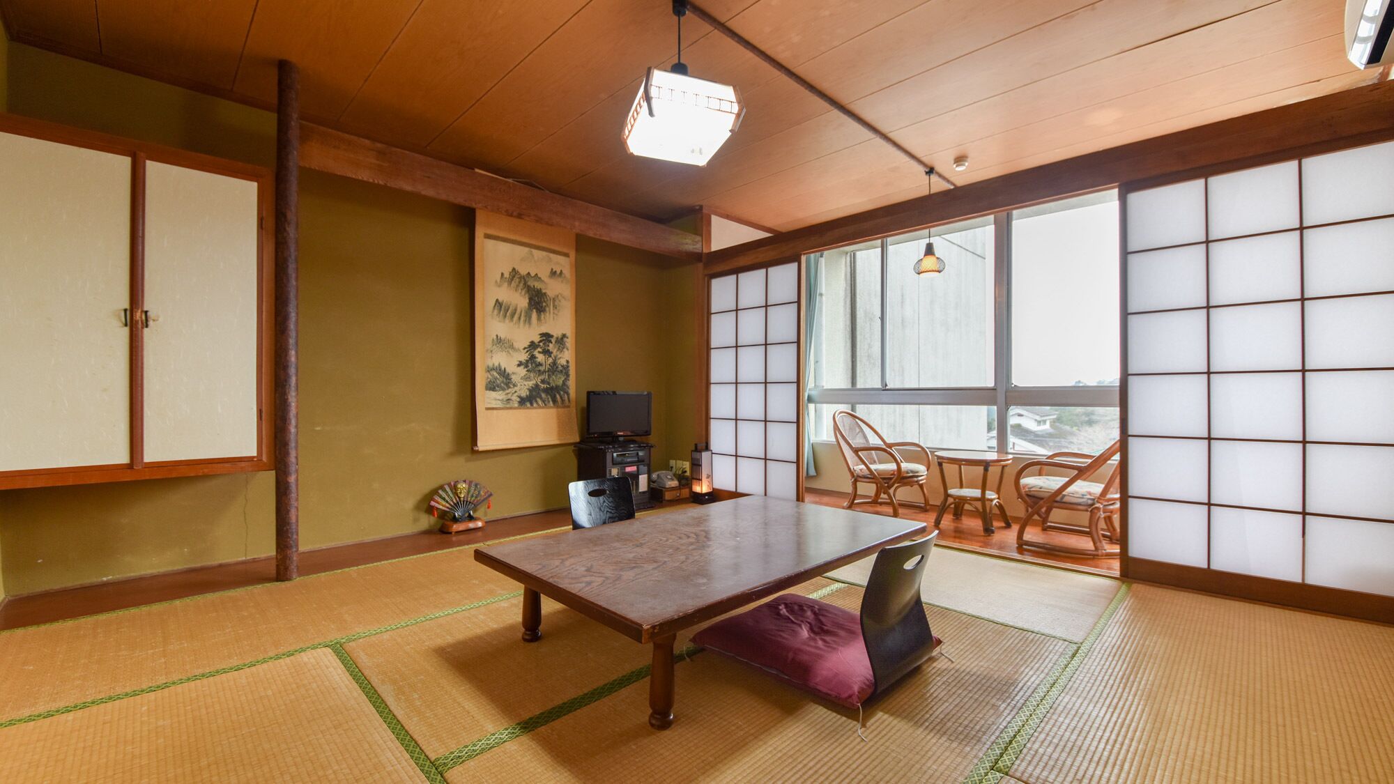 A traditional Japanese room with tatami flooring, a low table, a television, and sliding doors.