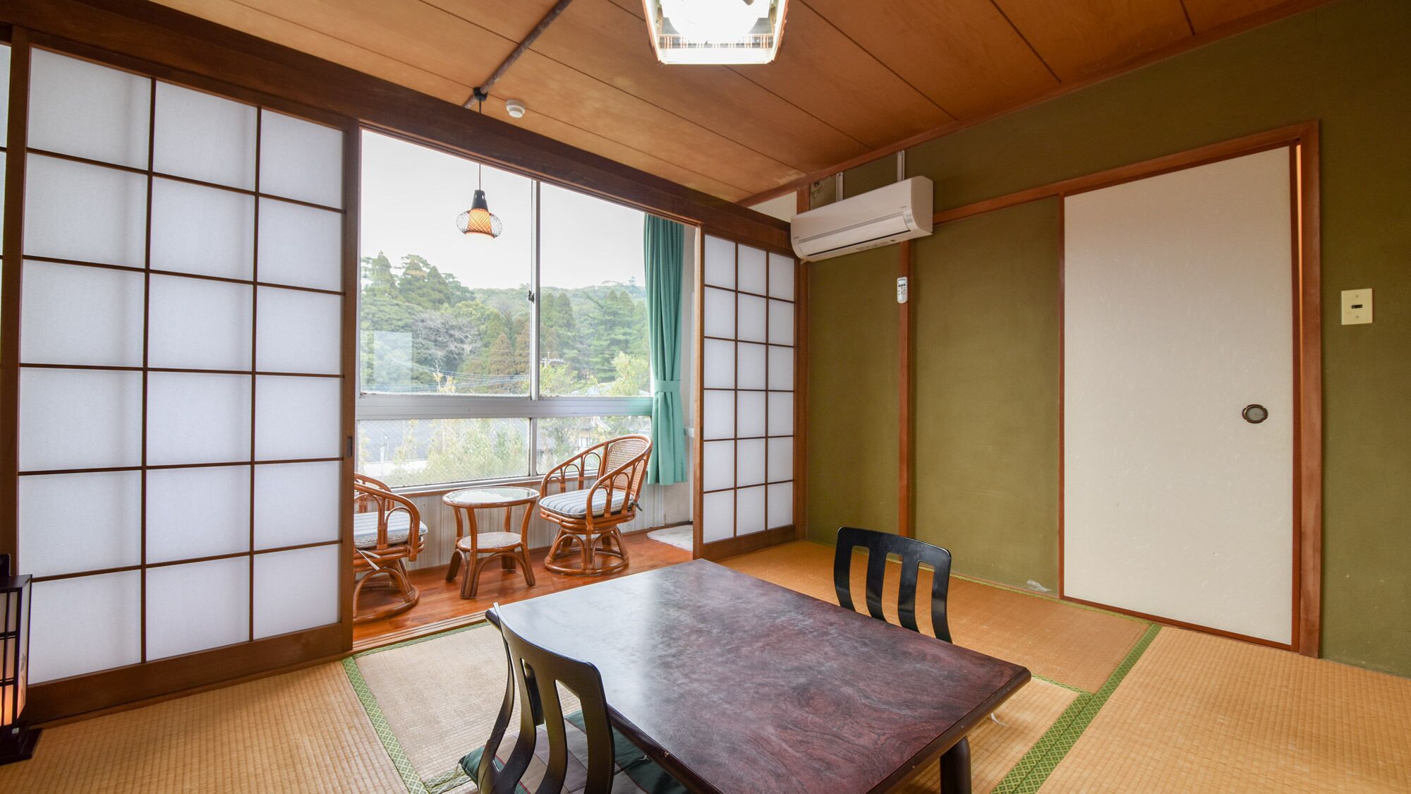 A traditional Japanese room with tatami flooring, a wooden table, and a view through shoji screens.