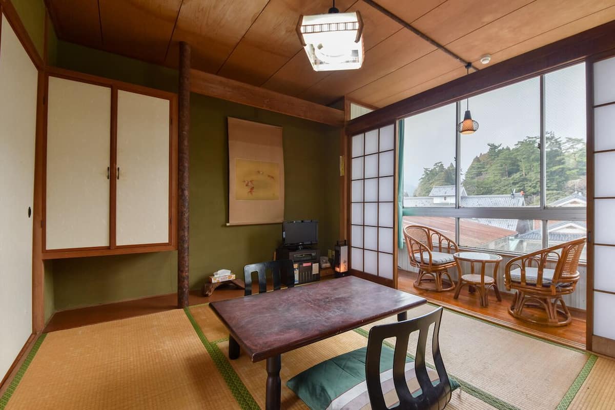 Una habitación tradicional japonesa con suelo de tatami, una mesa baja y puertas correderas.