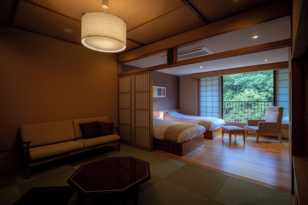 A hotel room with a sofa, a bed, a chair, a table, and a view of the outdoors.