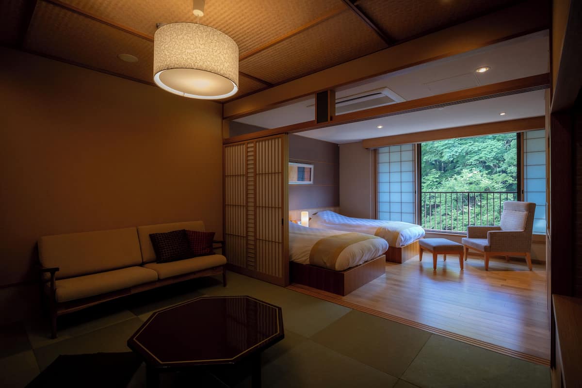 A hotel room with a sofa, a bed, a chair, a table, and a view of the outdoors.
