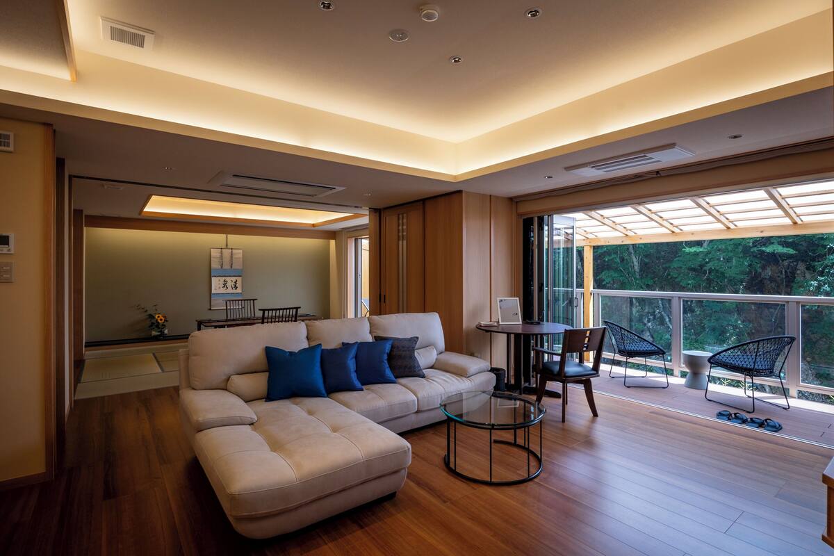 A modern living room with a sofa, a glass coffee table, and a dining area with chairs.