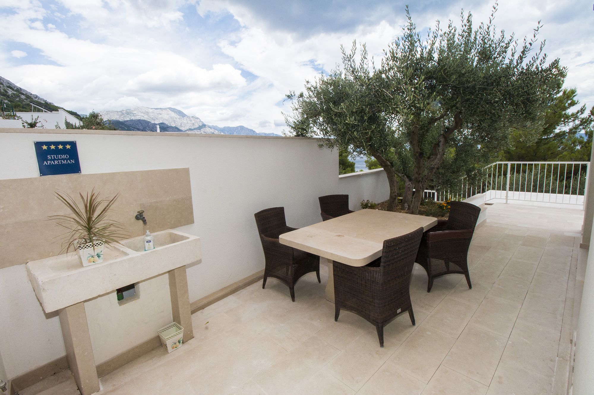 Patio esterno con tavolo e sedie, un lavello e un cartello che indica un appartamento studio.