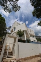 Um edifício moderno de dois andares com varanda, escadaria e portão.