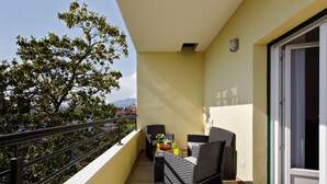 A balcony with wicker furniture, a table with fruit and drinks, and a view of trees and buildings. - Luxury beach apartment private parking (Split)