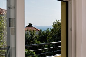 A view from a balcony with a railing, overlooking a building with a red-tiled roof and dense greenery. - Luxury beach apartment private parking (Split)