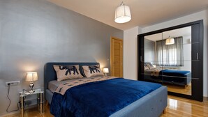 A modern bedroom with a large bed, bedside lamps, a mirror, and a wooden door. - Luxury beach apartment private parking (Split)