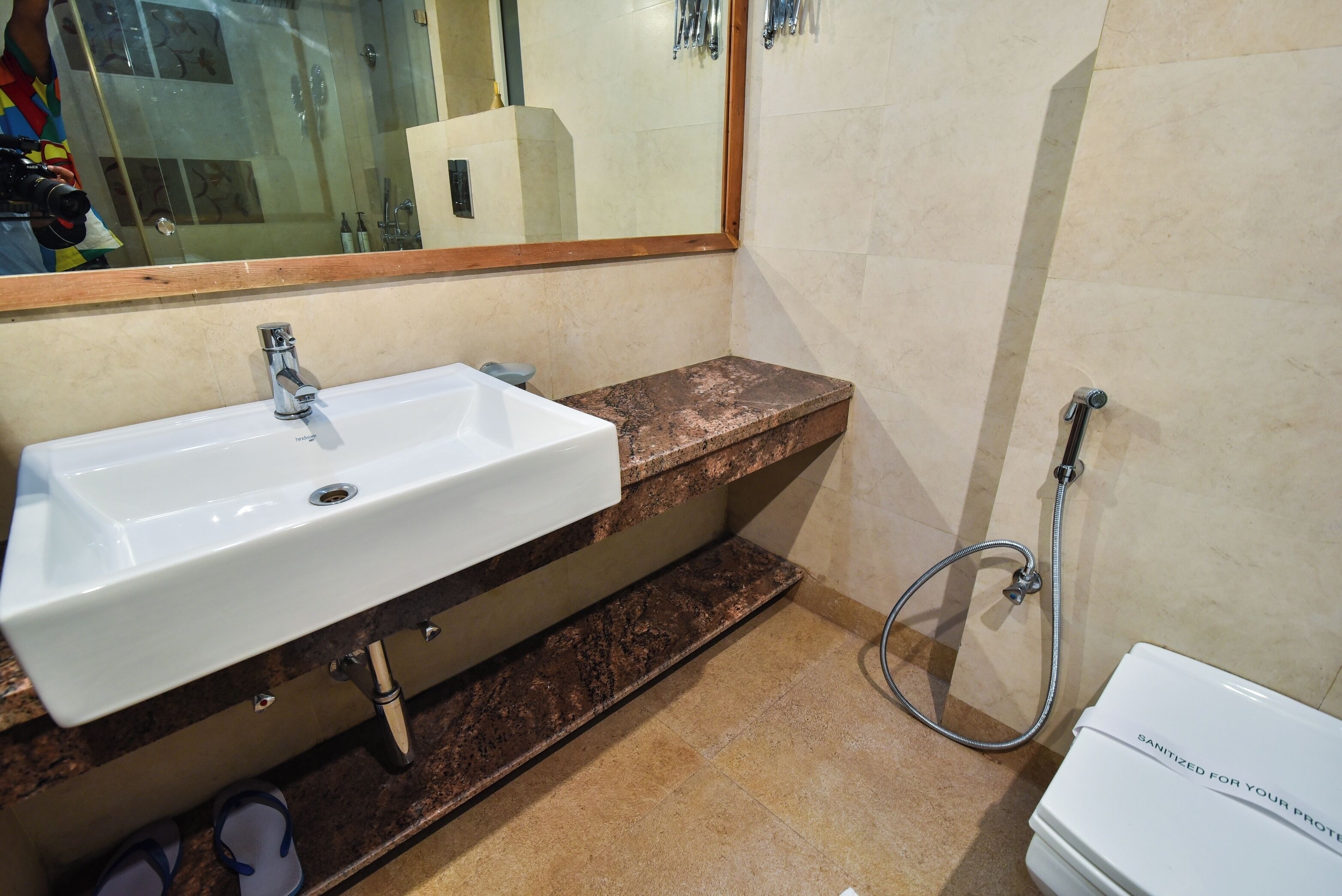 A bathroom with a white sink, a mirror, a shower, and a toilet.