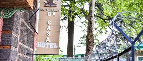 A sign for 'ARRIVE&REVISE D'S CASA HOTEL' with a logo featuring a tree and a figure.