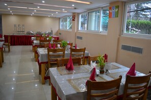 A dining area with multiple tables, chairs, and a buffet setup. - D'S CASA Hotel (Dharamshala)