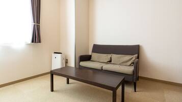 A room with a dark brown table, a grey sofa with beige cushions, and a white radiator.