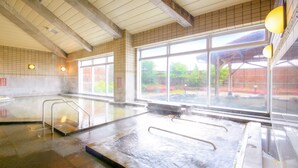 Una gran piscina interior con paredes de vidrio transparente, barandillas de metal y suelo de baldosas.