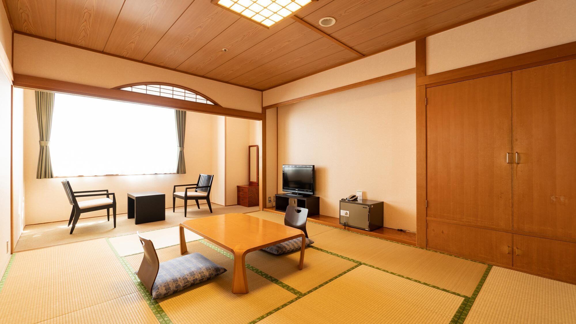 Una habitación japonesa tradicional con suelo de tatami, una mesa baja, un televisor y un armario.