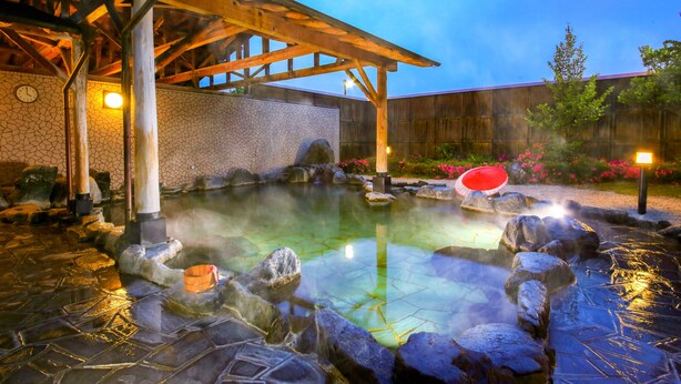 Un área de aguas termales con una pérgola de madera, baldosas de piedra y una valla de madera.