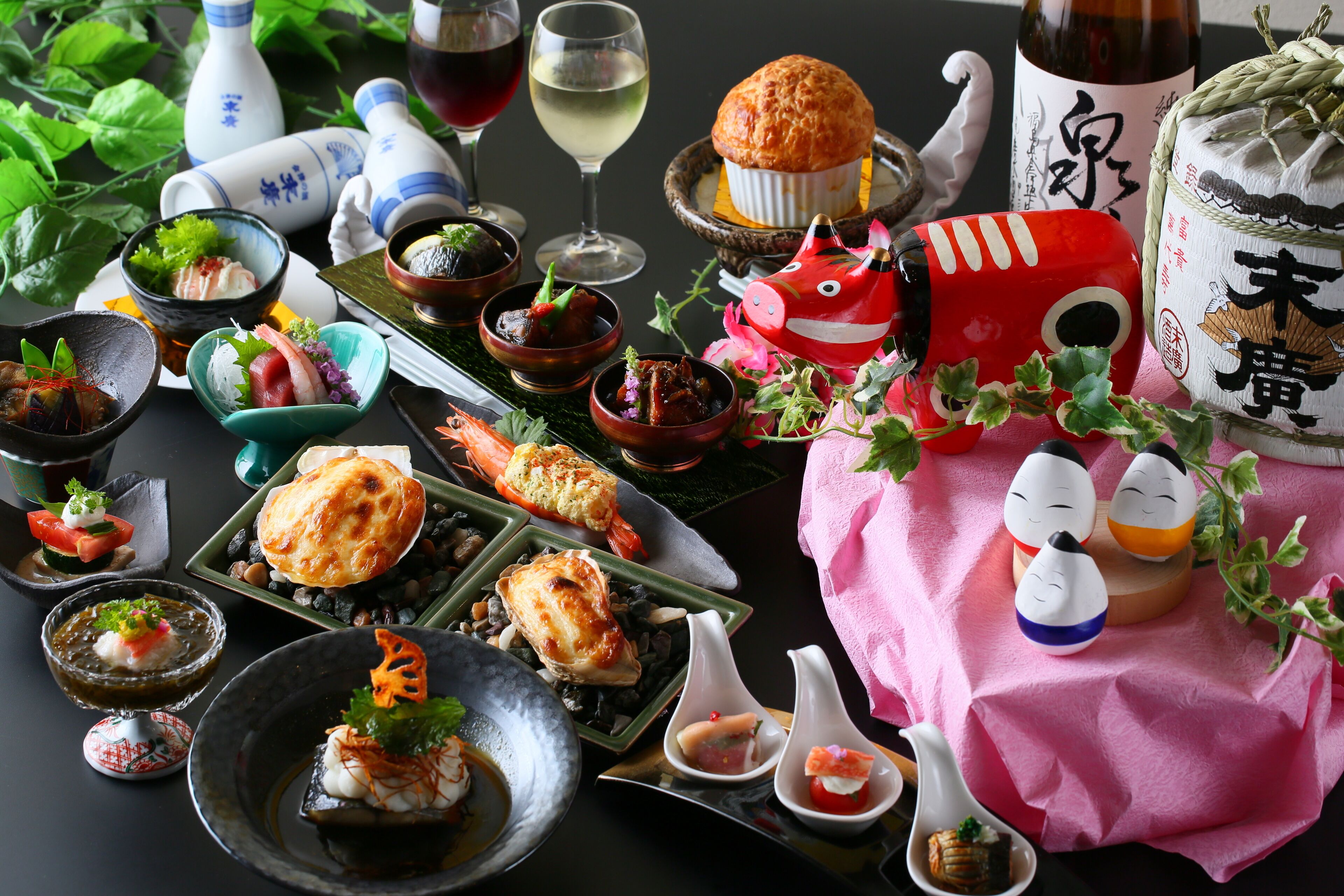 A variety of dishes and drinks on a table, including sushi, sashimi, and a red decorative item.