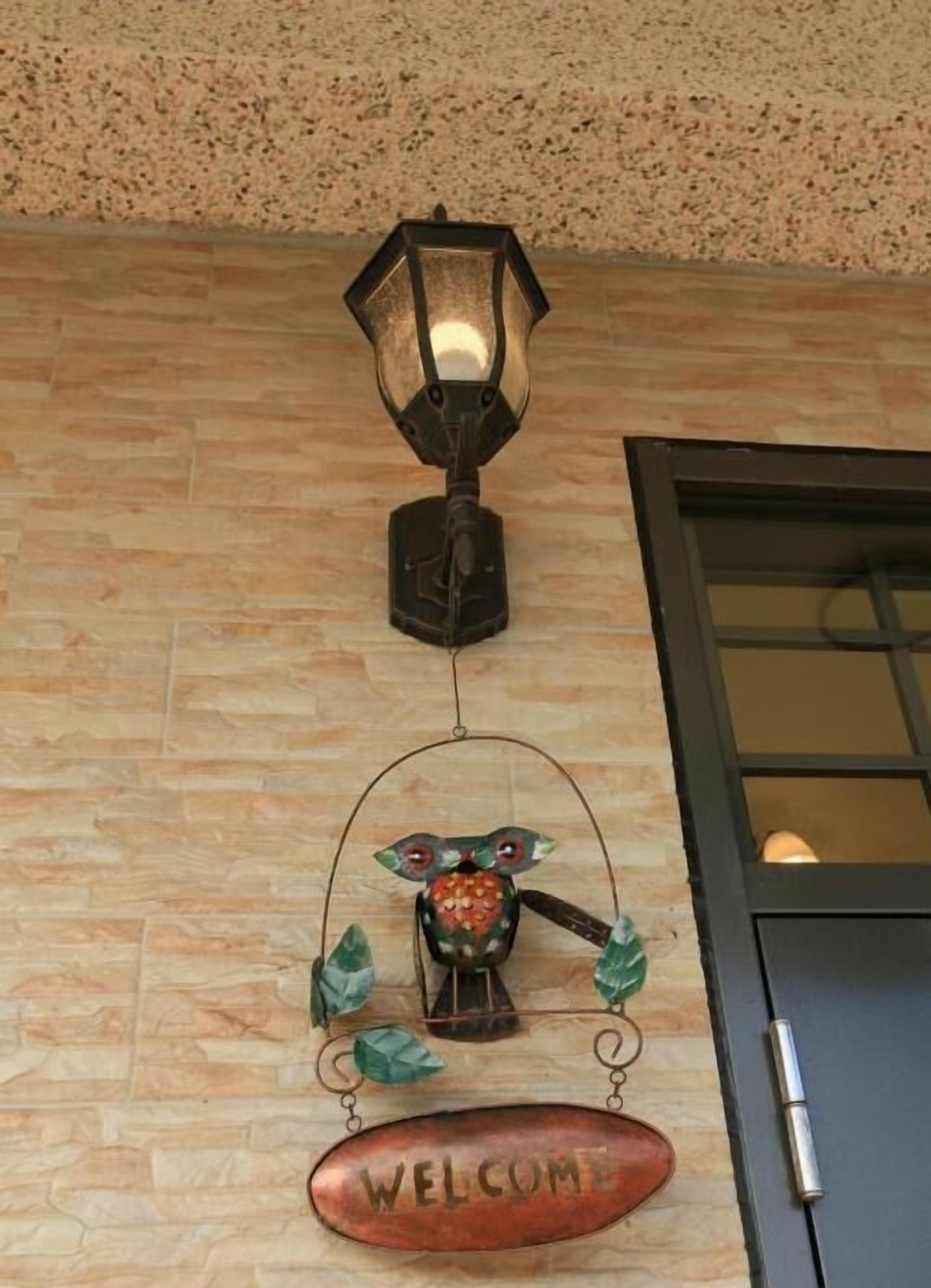 A welcome sign, a wall-mounted lamp, and a door with a view of the outside.