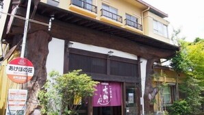 A building with a traditional architectural style, featuring a wooden overhang above the entrance. There are signs indicating a restaurant and a return service. - Kyomachi Onsen Akebonosou (Ebino)