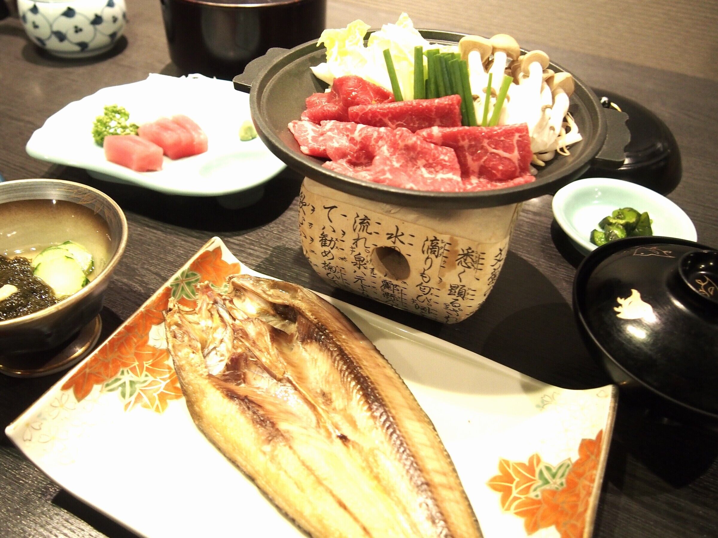 A meal with various dishes including fish, vegetables, and meat.