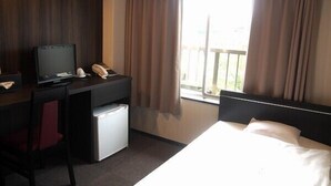 A hotel room with a bed, a desk with a computer, a telephone, and a small refrigerator. - Kyomachi Onsen Akebonosou (Ebino)