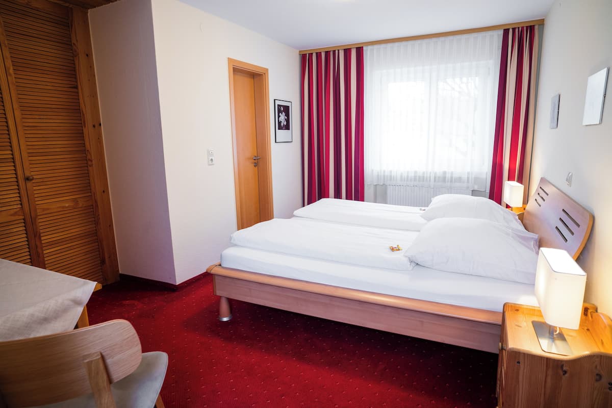 A hotel room with a wooden bed, a desk, and a chair.