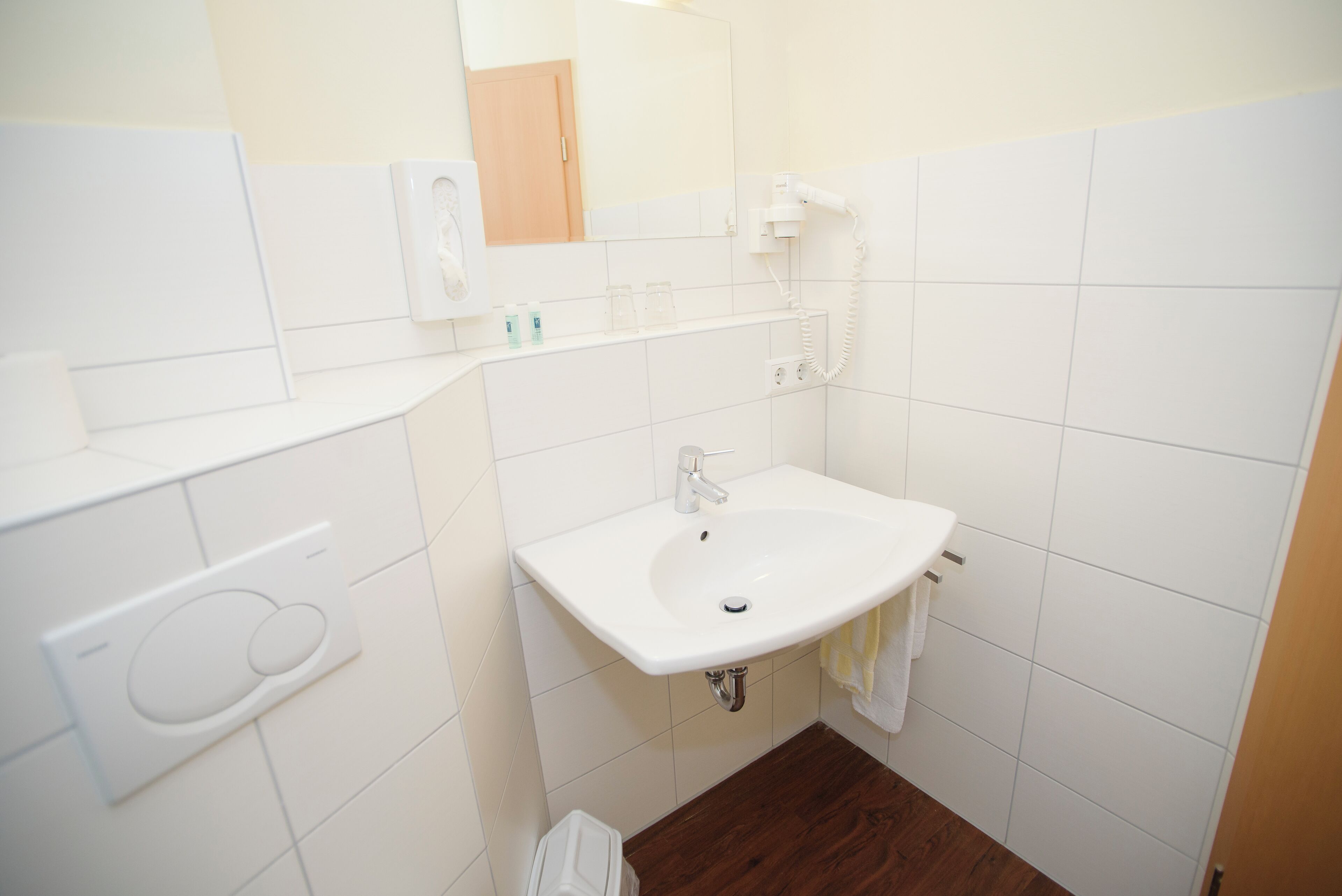 Ein Badezimmer mit Waschbecken, Spiegel, Fön und Handtuchhalter.