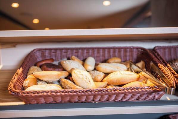 A display of various breads in wicker baskets.