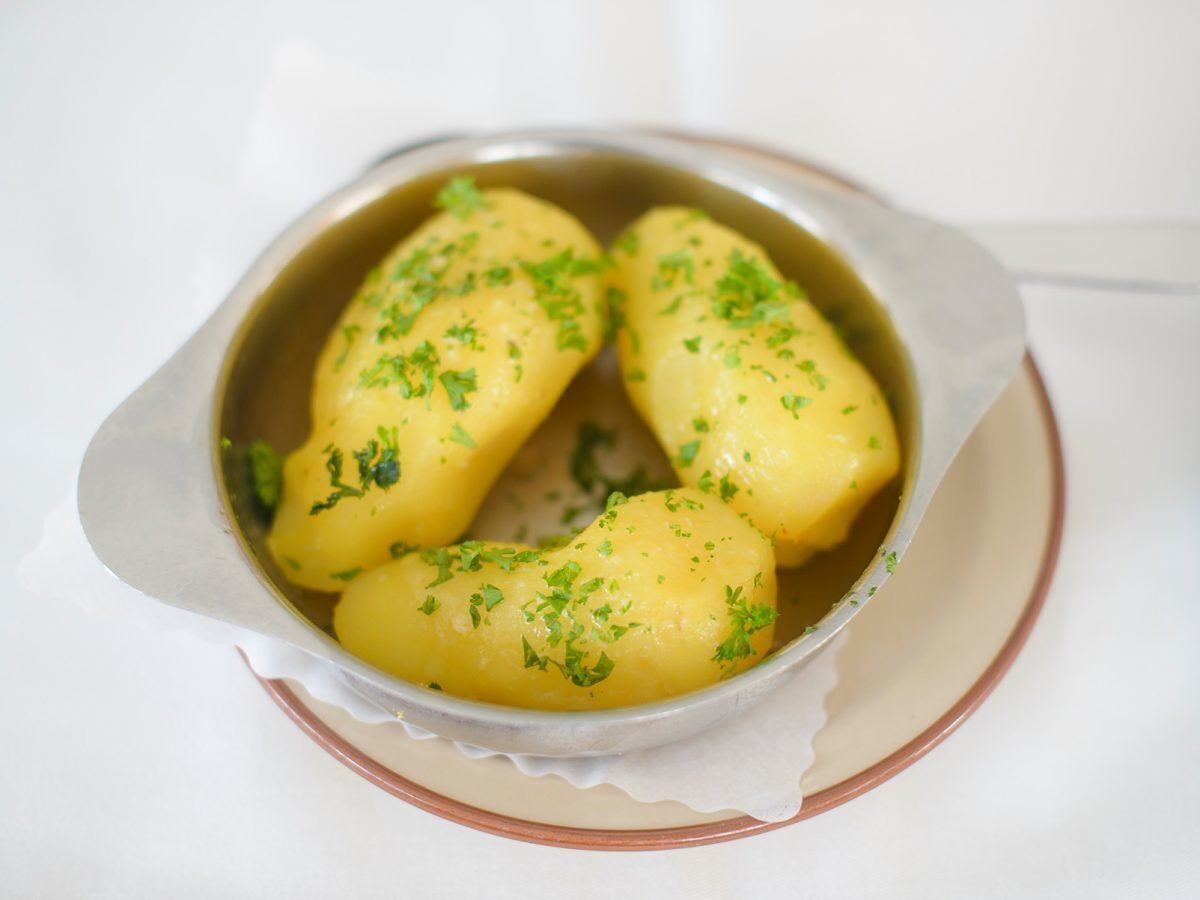 A bowl of boiled potatoes garnished with parsley.