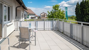 A balcony with a table and chairs, a view of houses, and a sign in the distance. - Hotel Landgasthof Linde (Deggenhausertal)