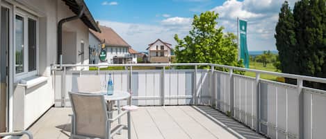 Een balkon met een tafel en stoelen, een uitzicht op huizen en een bord in de verte.