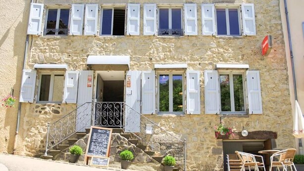 Un edificio de piedra de dos plantas con un letrero que dice "HOTEL RESTAURANT".