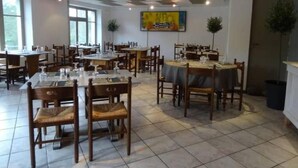 Un comedor con varias mesas y sillas, suelo de baldosas y techo con un diseño geométrico.