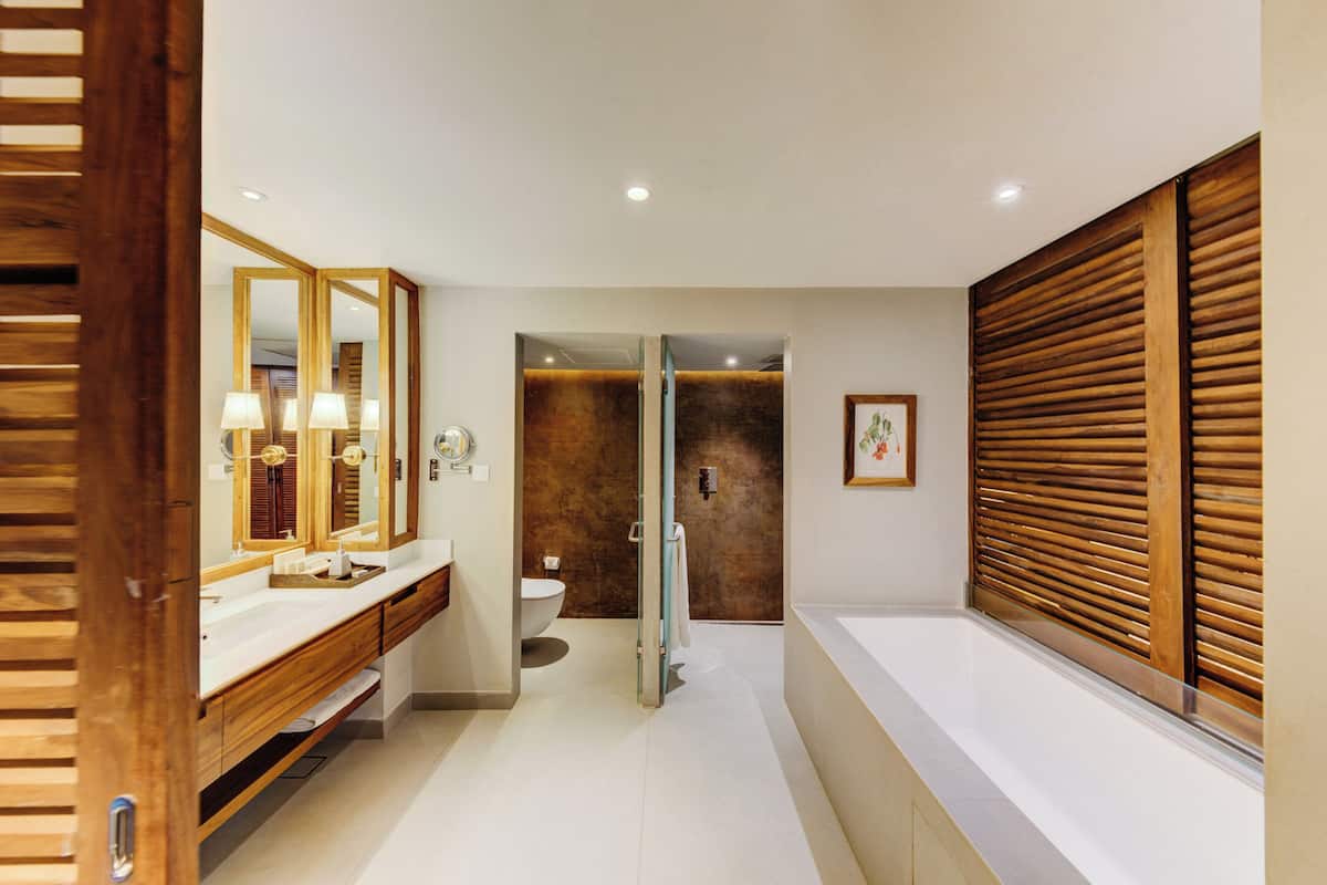 Un baño moderno con tocador de madera, un espejo grande y una bañera.