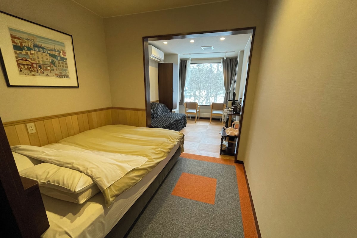 A hotel room with a bed, a chair, a desk, and a window.