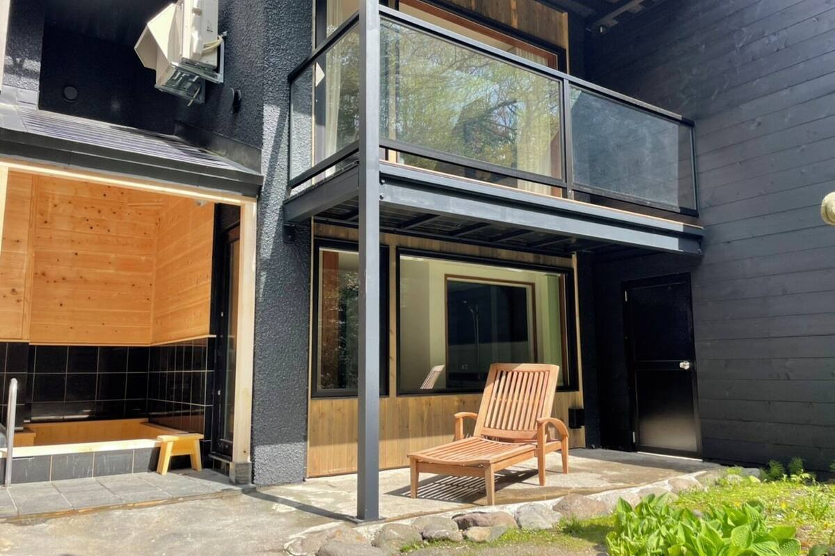 A modern two-story building with large windows, a wooden deck, and a stone pathway.