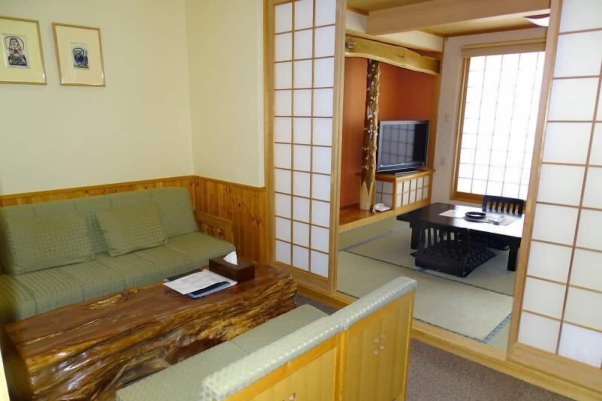 A room with a wooden sofa, a small table, a television, and a sliding door with a grid pattern.