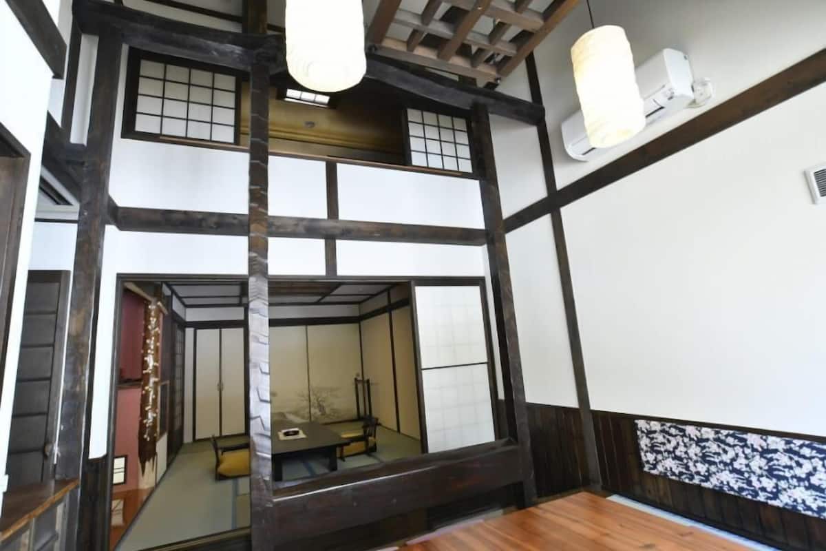 A traditional Japanese room with tatami flooring, sliding doors, and a low ceiling with exposed beams.