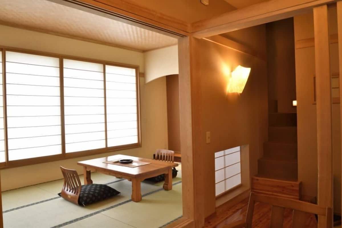 A traditional Japanese room with tatami flooring, a low table, and a chair.