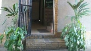 A building entrance with a metal gate, a sign reading "CINGAKI", and potted plants on either side. - Cingaki Hotel (Mombasa)