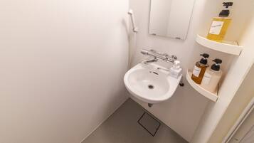 Een witte badkamer met een wastafel, een spiegel en planken met toiletartikelen.
