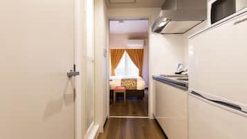 A narrow hallway with a kitchen area on one side and a bedroom on the other.