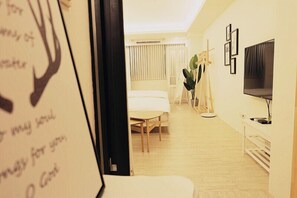 Ein modernes Hotelzimmer mit Bett, Schreibtisch, Stuhl, Fernseher und Pflanze.