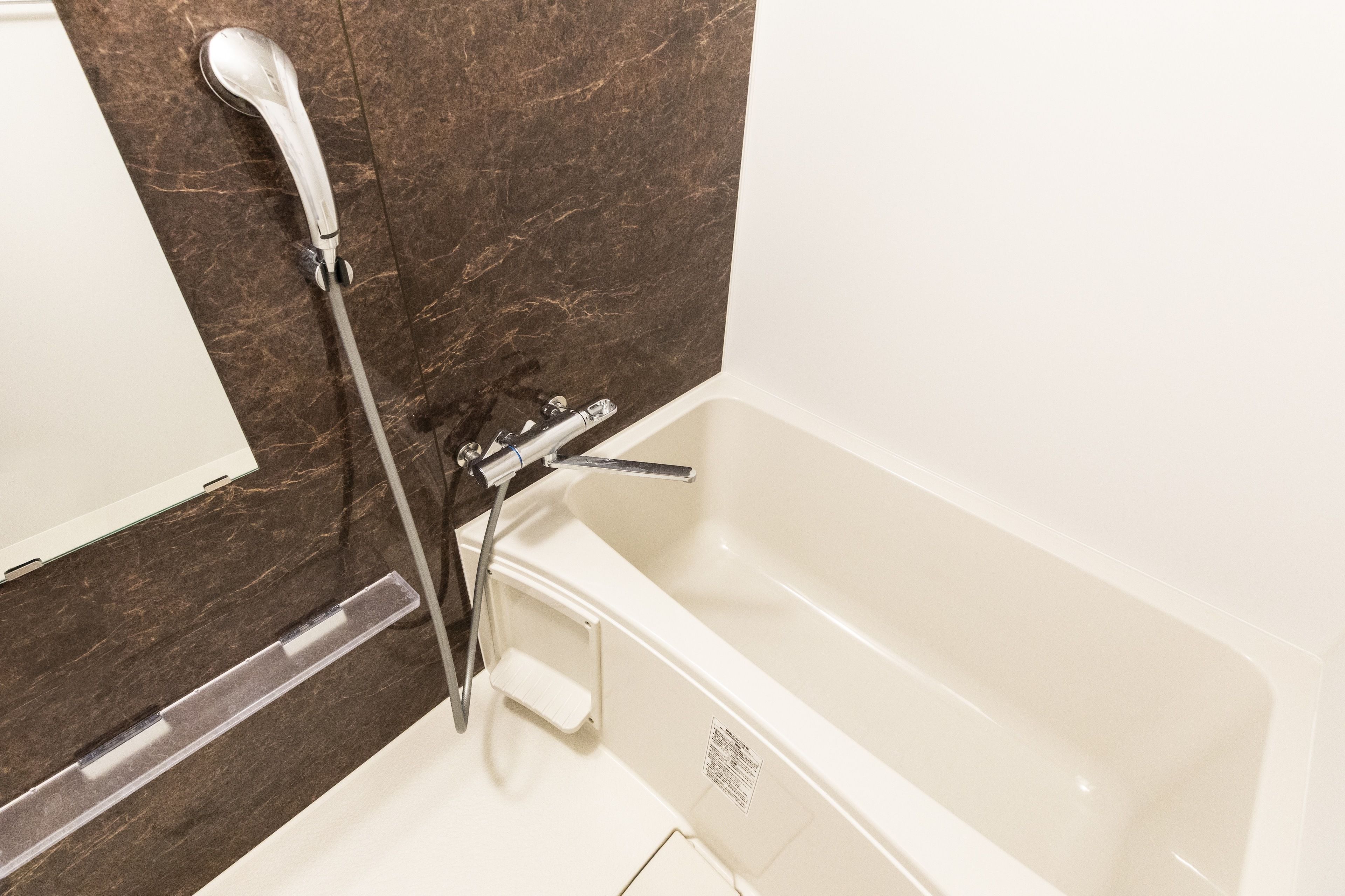 A bathroom with a bathtub, a showerhead, and a white sink.