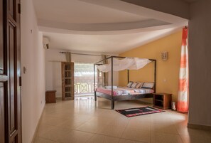 A bedroom with a four-poster bed, a small bedside table, a nightstand, and a window with curtains. - Cho ka Cottages (Mombasa)