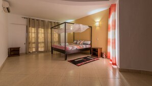 A bedroom with a four-poster bed, a small bedside table, a nightstand, and a wall-mounted lamp. - Cho ka Cottages (Mombasa)