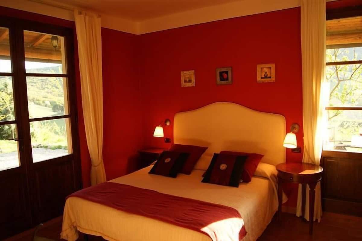 A bedroom with a large bed, two bedside tables, and a window with curtains.