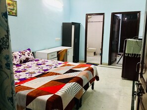 Cozy retreat with a bed, desk, and wardrobe, featuring a bathroom with a toilet and sink.