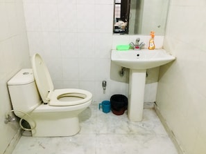 Bathroom features a white toilet, sink, and mirror, with a window and tile flooring.