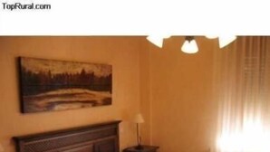 Een opgemaakt bed met hoofdbord, nachtkastje en lamp.