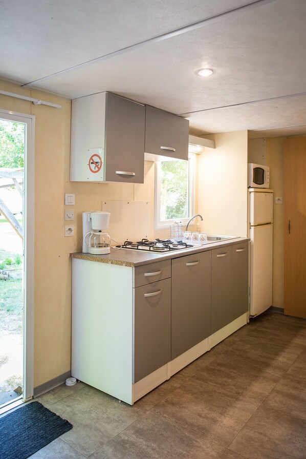 A compact kitchen with a gas stove, a microwave, and a refrigerator.